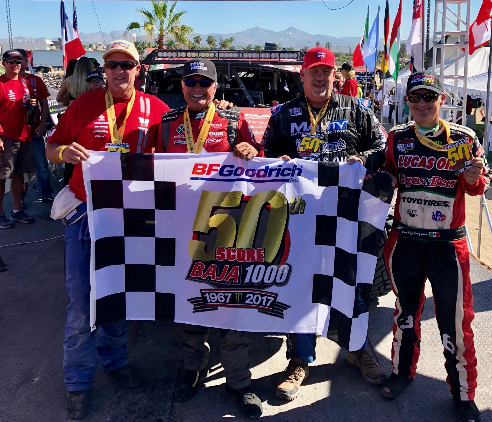 Pilotos con la bandera a cuadros en la meta de la 50ª Baja 1000